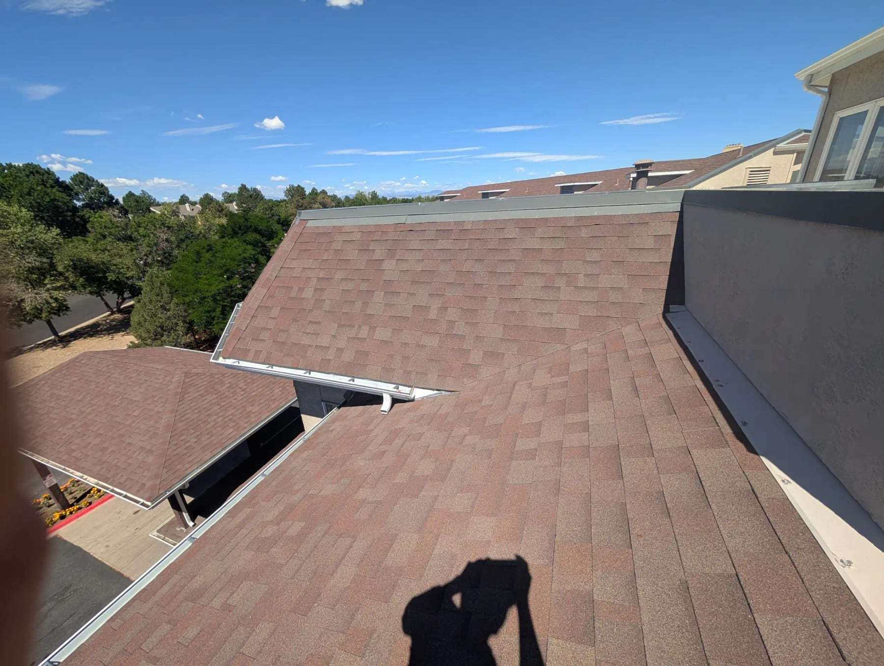 View across the shingled roof of a house toward the neighbors